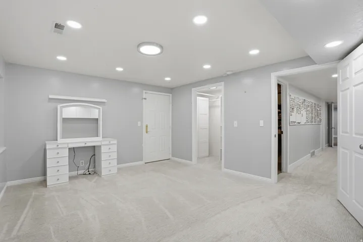 Soft carpeted flooring throughout a light gray painted room featuring multiple recessed ceiling lights and a central flush-mount fixture