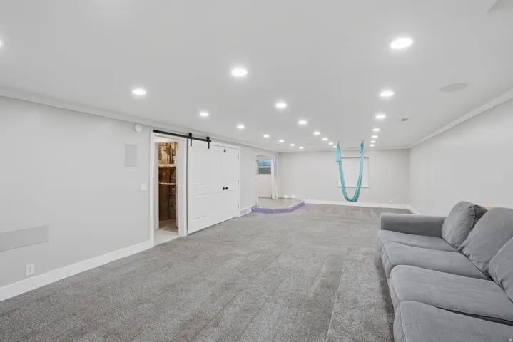 Spacious interior featuring recessed lighting, light gray walls, gray carpet flooring, and white trim