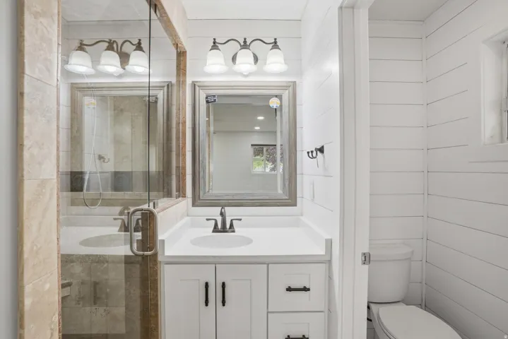 Modern bathroom featuring a white vanity with a single sink, quartz countertop, and dark bronze faucet