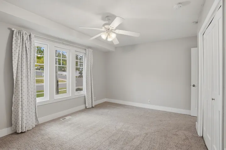 Bright interior with a triple window array, light gray wall paint, and a textured carpet