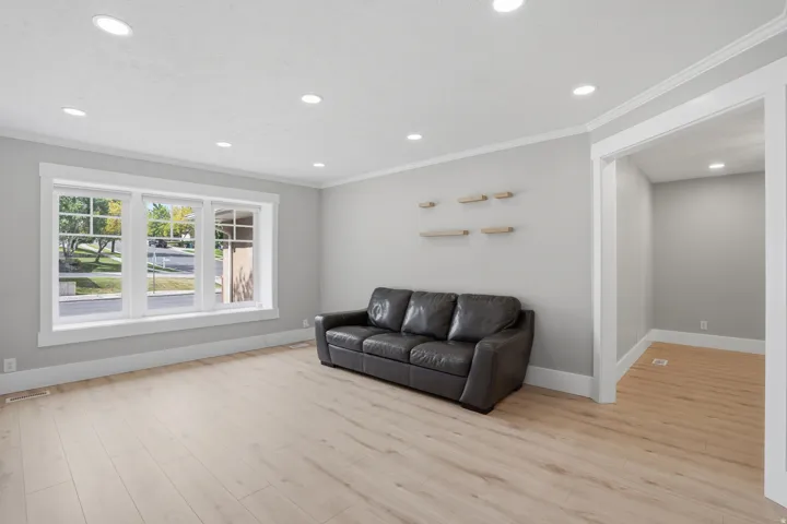 Spacious room featuring light wood-finish flooring, recessed ceiling lighting, and a large multi-pane window with white trim