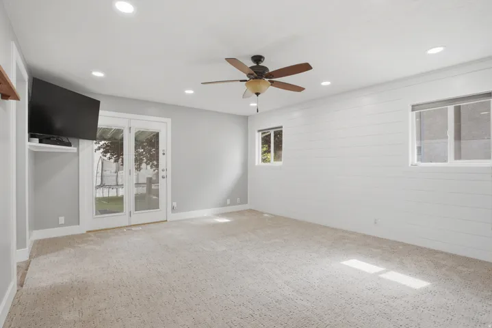 Spacious room featuring light-colored carpeting, recessed lighting, and a ceiling fan