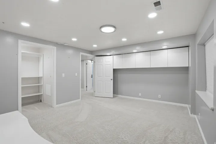 Light gray carpeting with recessed lighting and a central flush-mount fixture