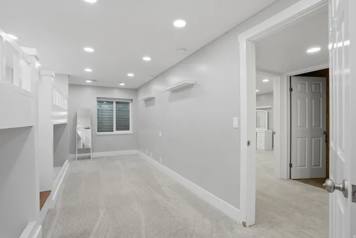 Spacious room featuring light gray carpet flooring, recessed ceiling lighting, and a white framed window