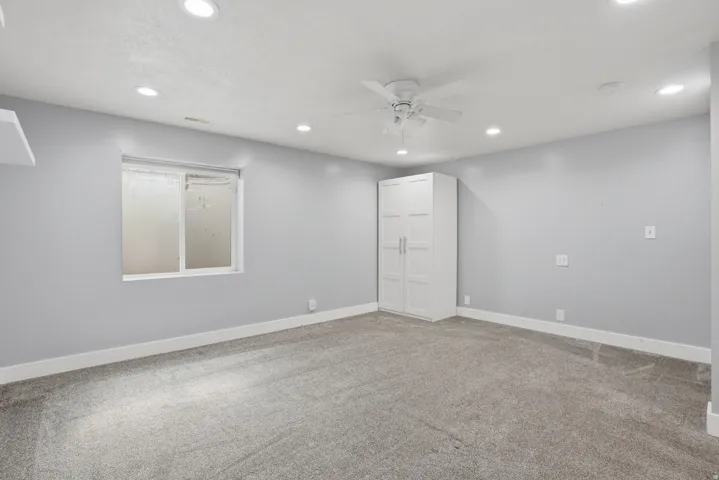 Spacious room featuring light gray walls, gray carpet, and white trim