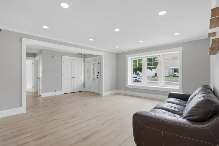 Spacious living area featuring wood-finish flooring, recessed lighting, and a large window with white trim