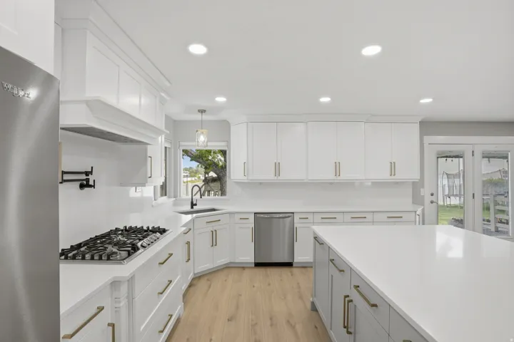 Modern kitchen featuring white shaker cabinetry, stainless steel appliances, a center island with countertop seating, recessed lighting, and wood-finish flooring