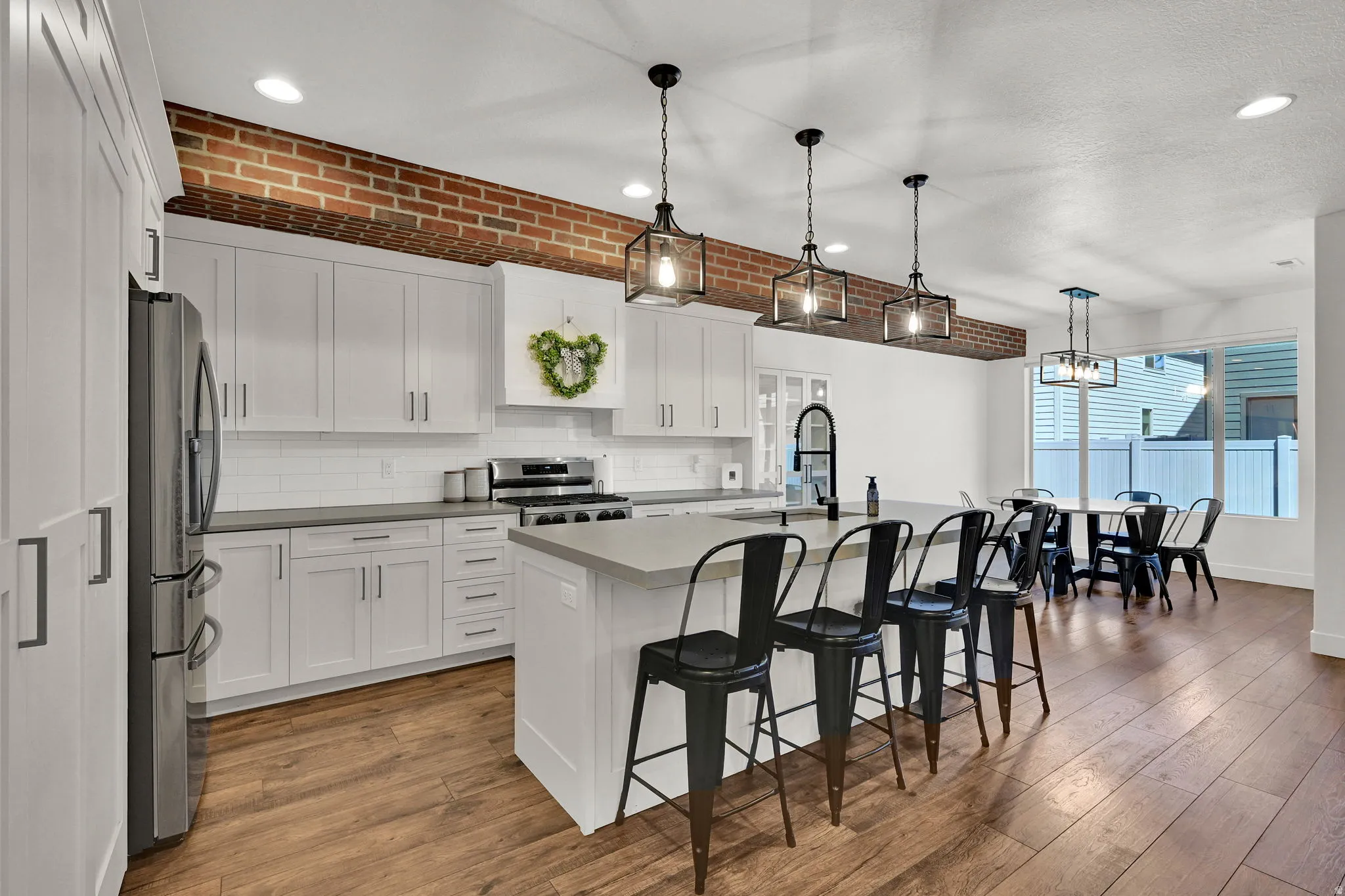 Modern kitchen featuring white shaker cabinetry, stainless steel appliances, a subway tile backsplash, and a large central island with seating