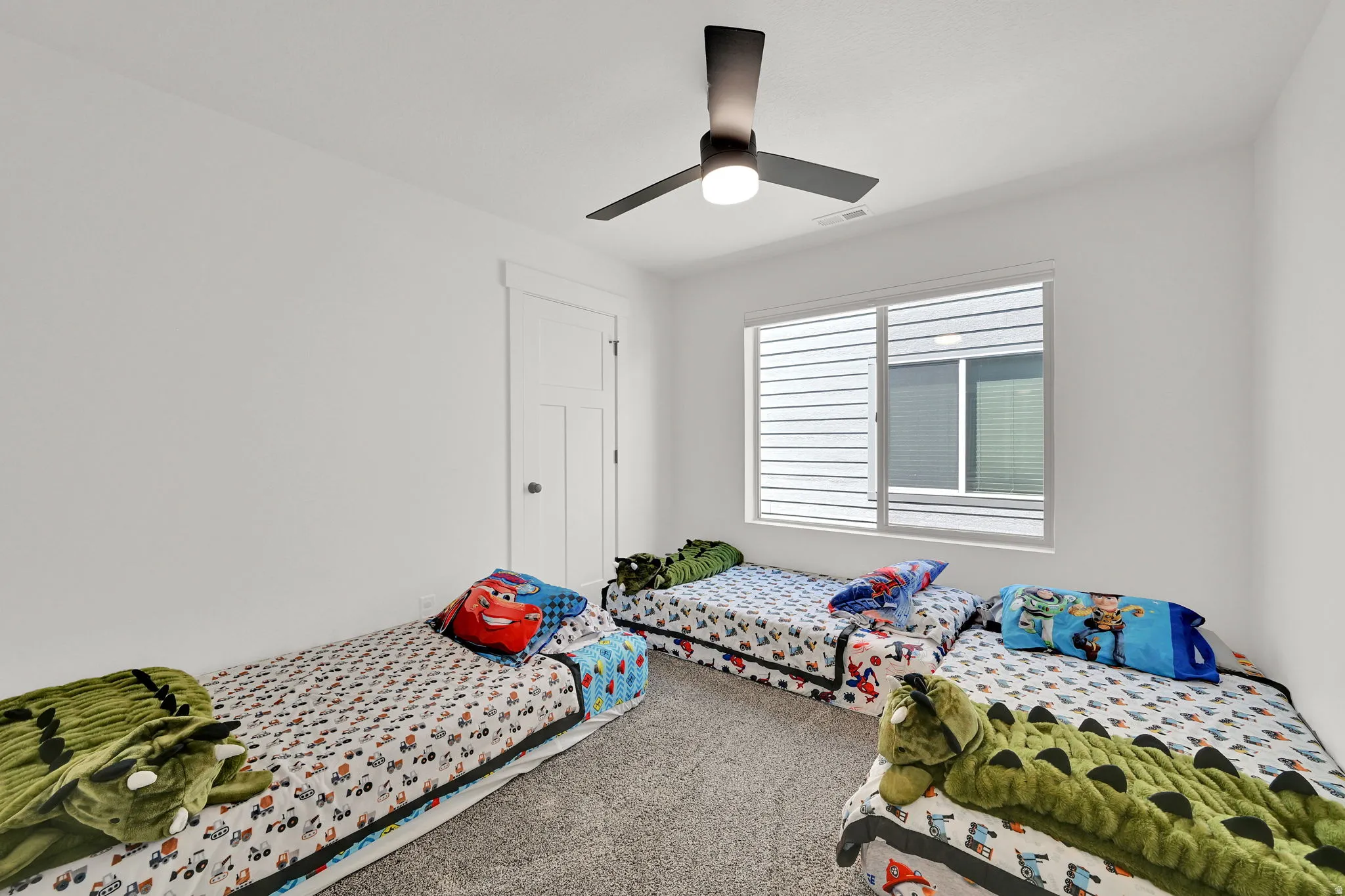 Bright room featuring a contemporary ceiling fan with integrated lighting, a large window with horizontal blinds, a white paneled door, and neutral-toned carpeting