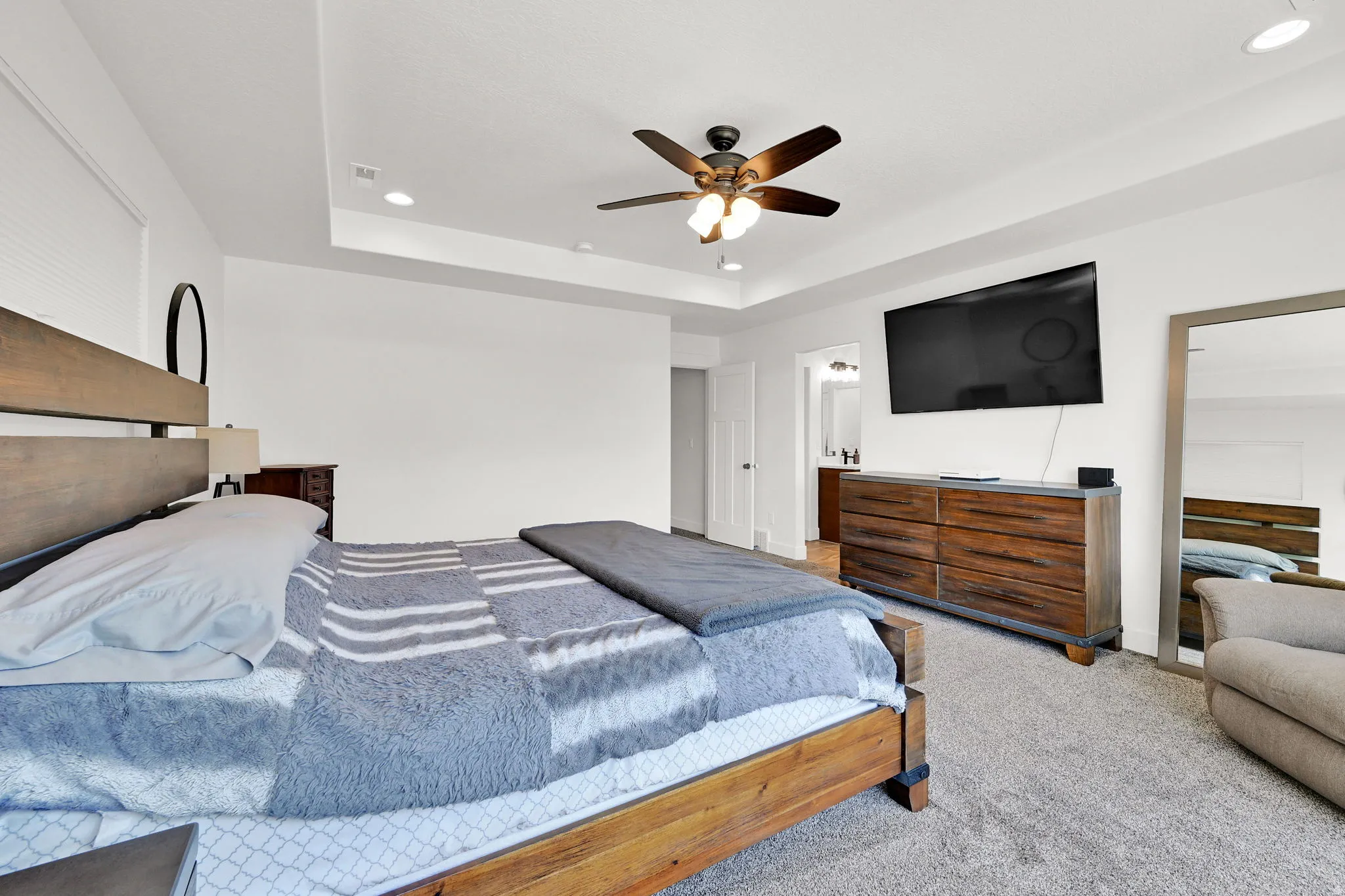 Spacious room featuring tray ceiling with recessed lighting and a ceiling fan