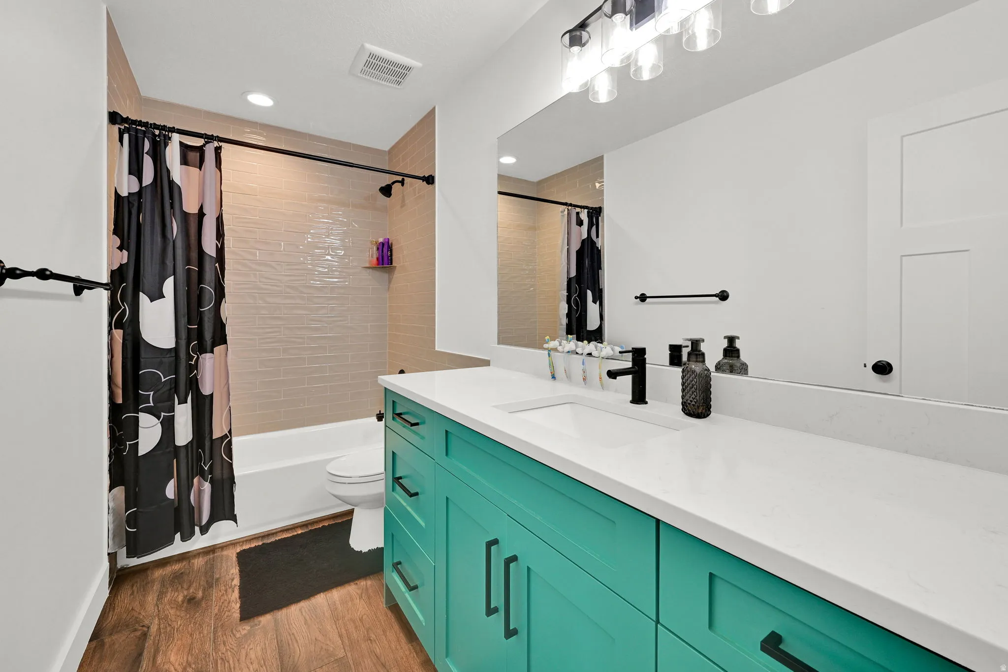 Modern bathroom featuring a teal vanity with a white countertop and integrated sink