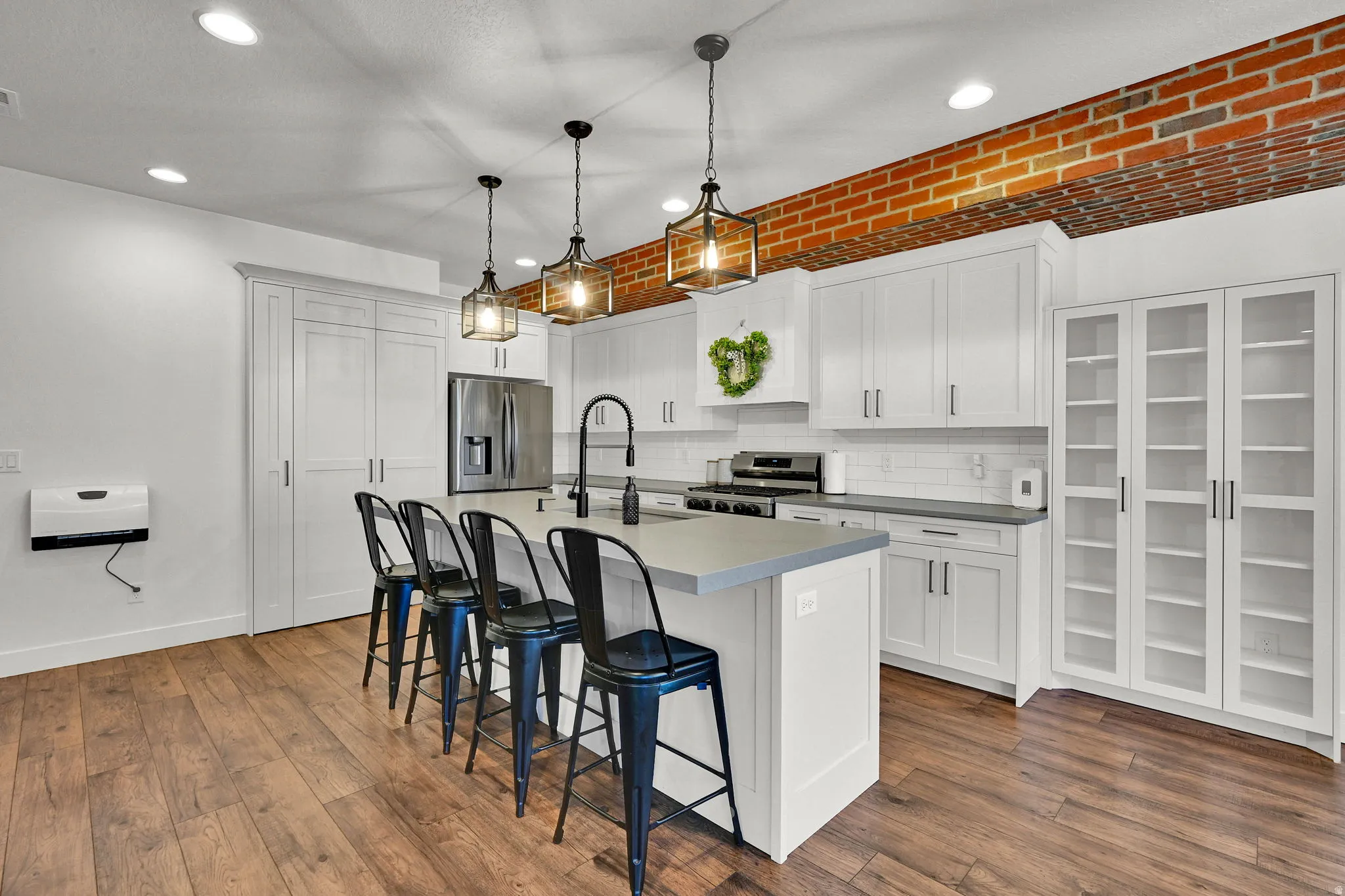 Kitchen featuring a central island with countertop seating, white shaker cabinetry, stainless steel appliances, and wood-finish flooring