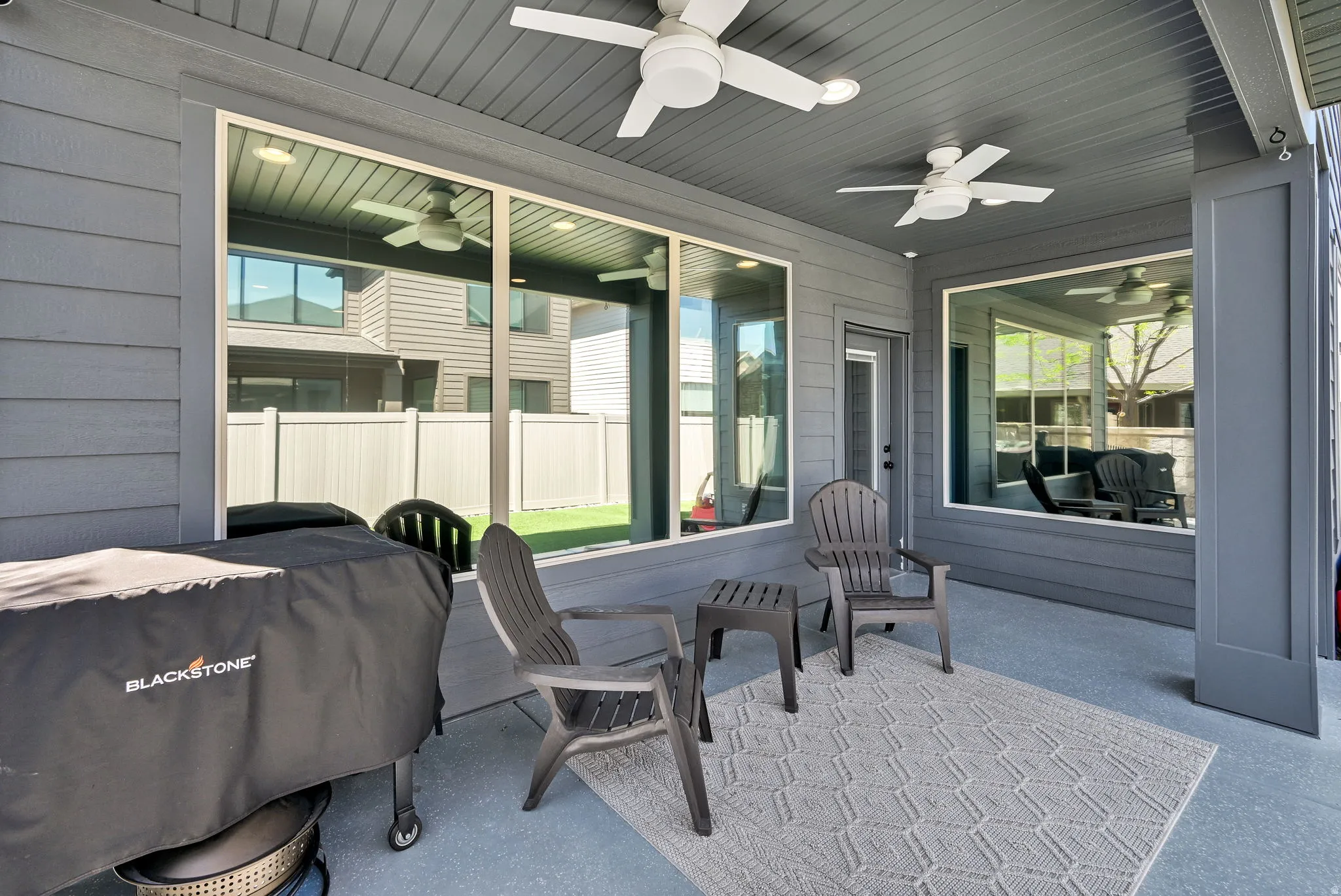Covered patio featuring two ceiling fans with integrated lighting, recessed lighting, and a durable concrete floor. *Notice the tinted windows.