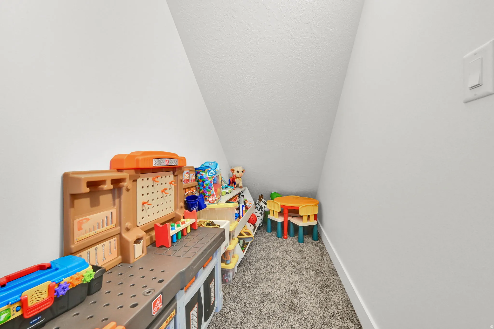 Carpeted nook featuring sloped ceilings and a neutral color palette