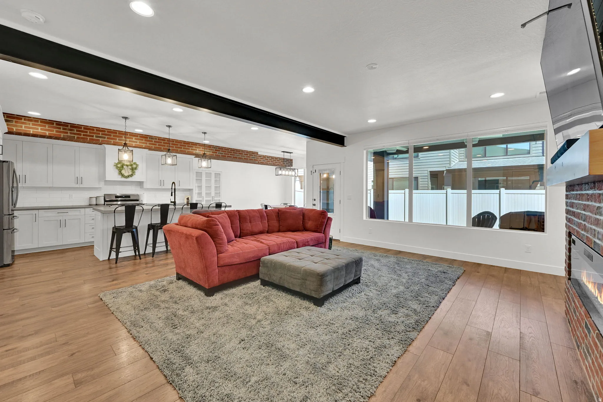 Open-concept living space featuring wood-finish flooring, recessed lighting, and a brick accent wall