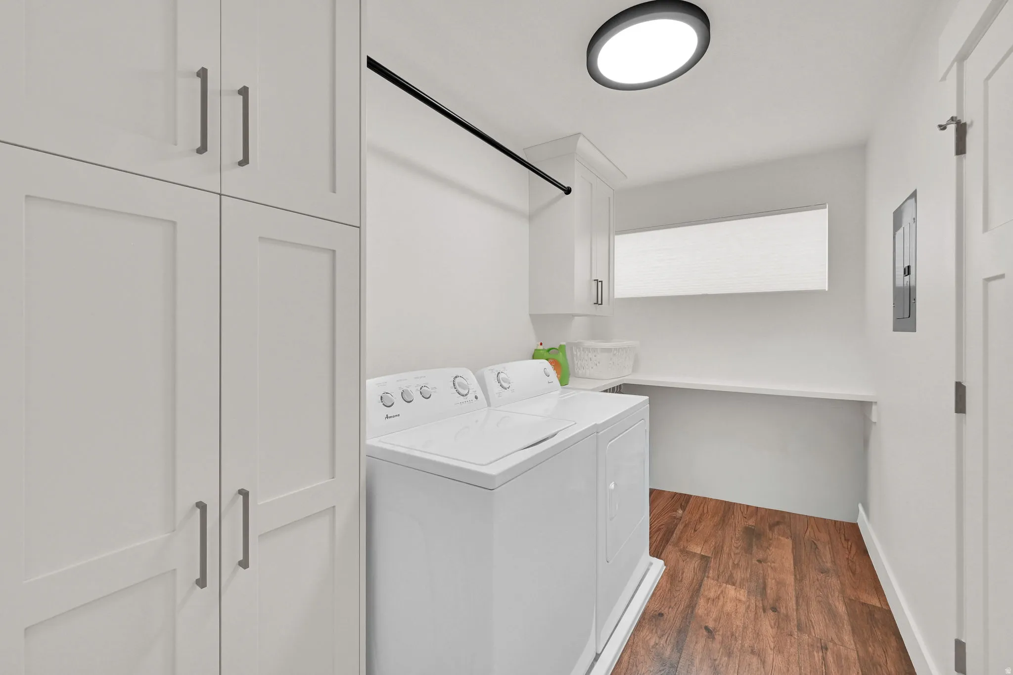 Dedicated utility space featuring extensive white cabinetry, wood-finish flooring, a functional countertop, and a ceiling-mounted light fixture