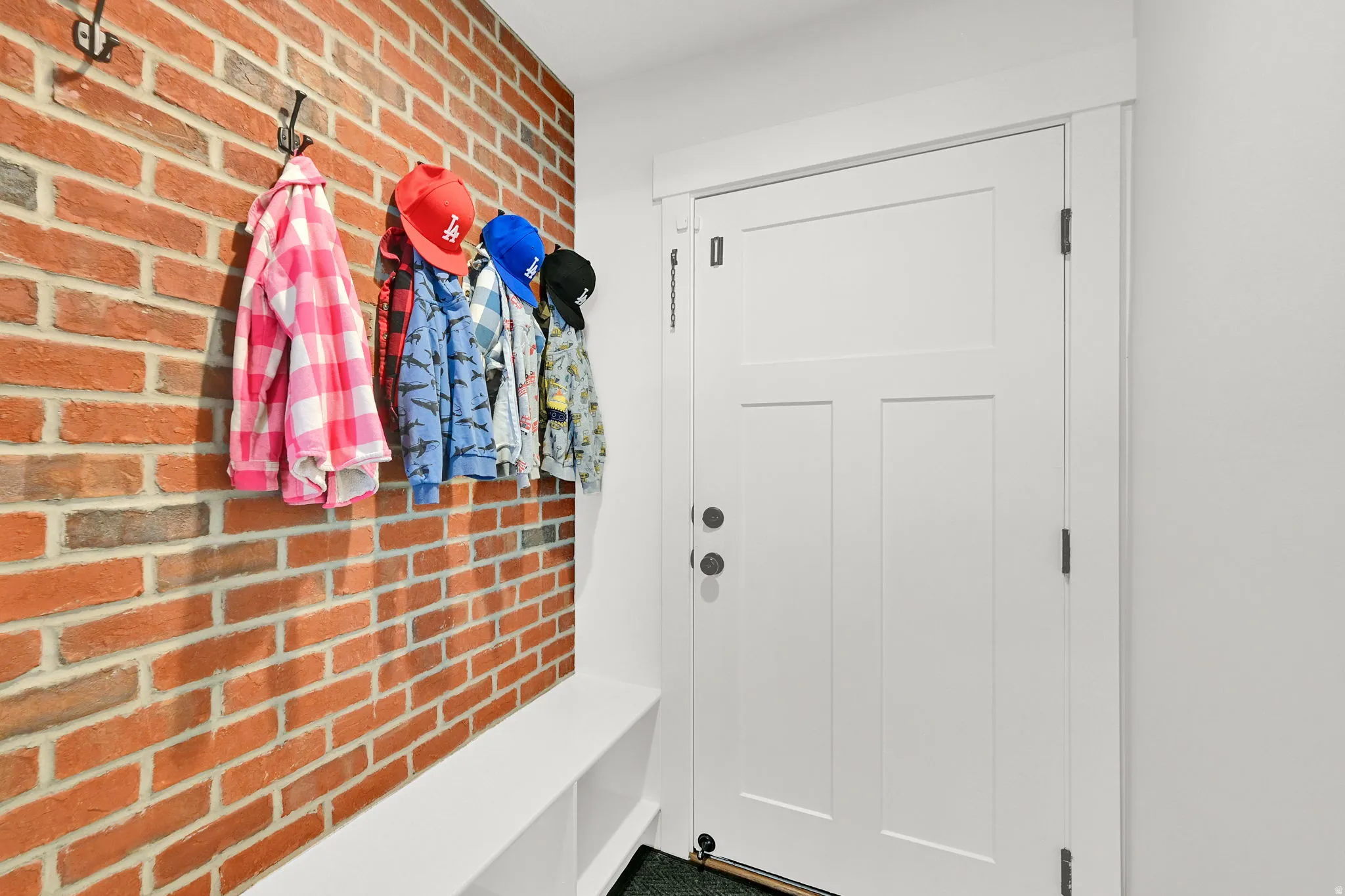 Textured brick wall with integrated coat hooks and a built-in storage bench