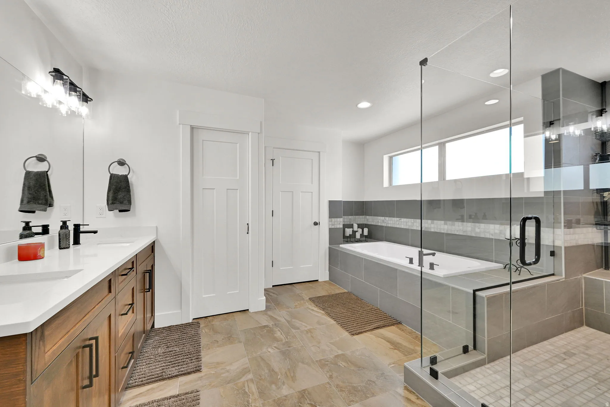 Expansive bathroom featuring a double vanity with wood-finish cabinetry and white countertops