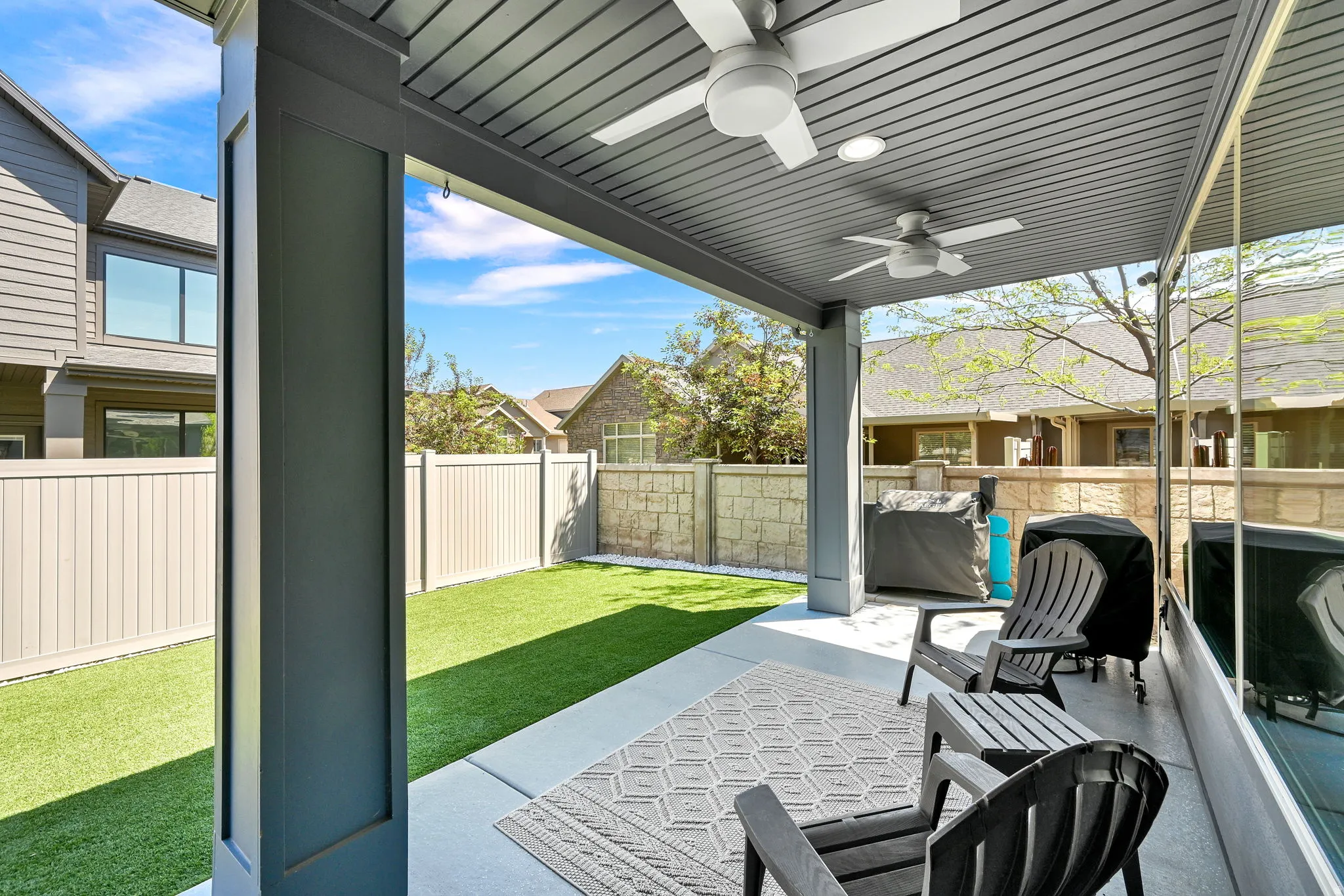 Covered patio with a concrete slab, slat ceiling, and two ceiling fans