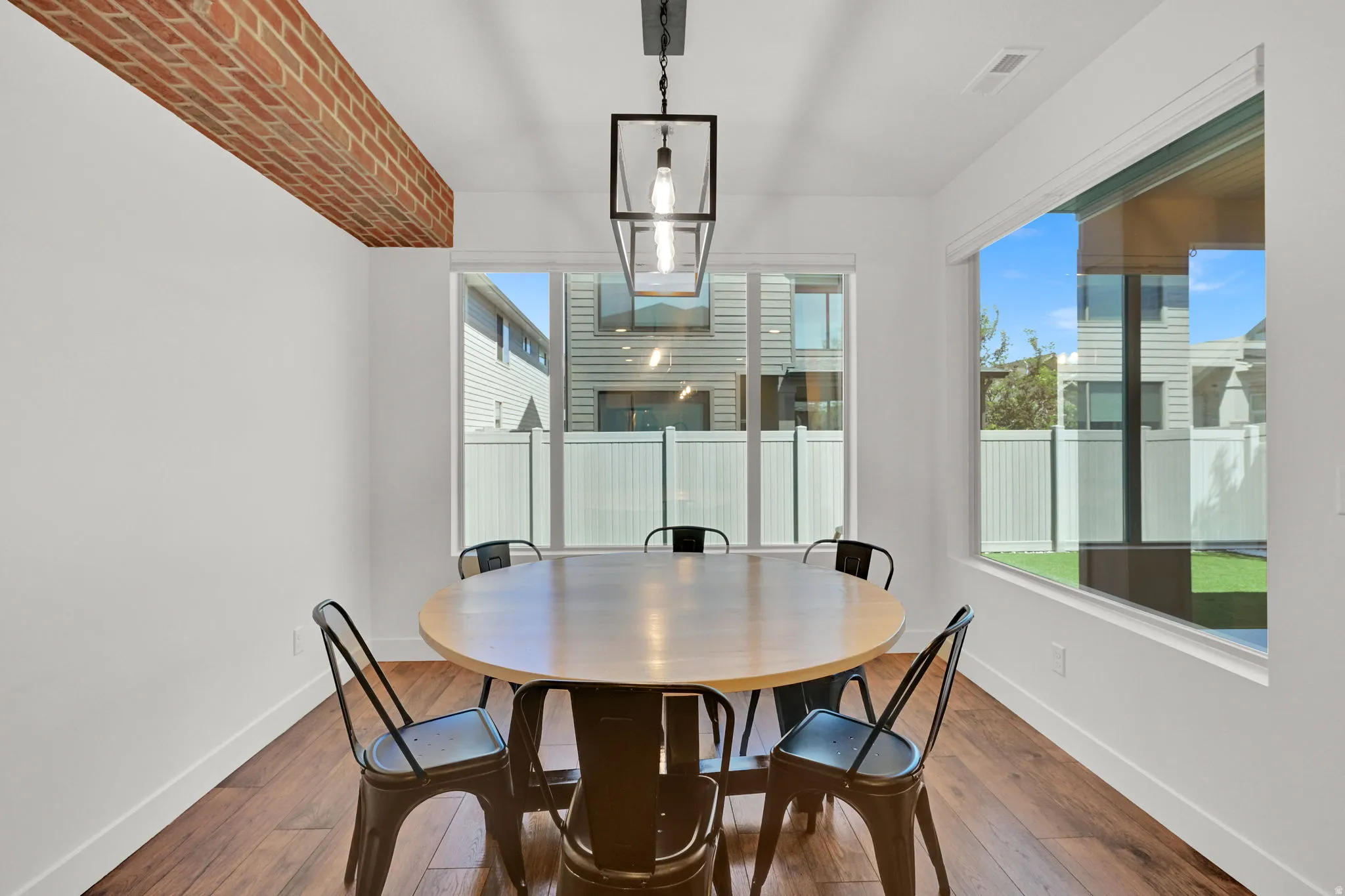 Dining area featuring wood-finish flooring, white baseboards, and a brick ceiling beam