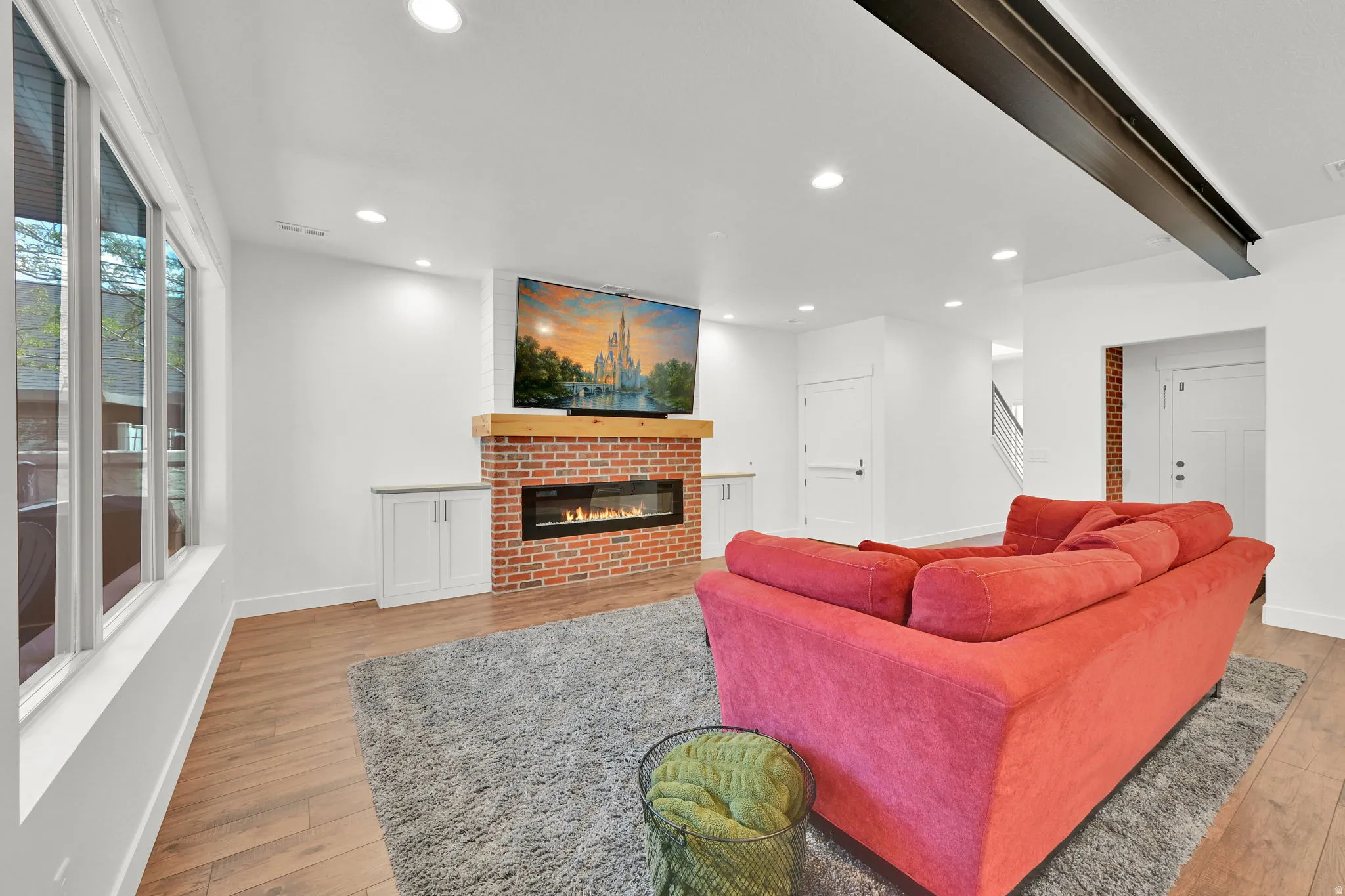 Living area featuring a brick fireplace with a wood mantle and a linear electric insert
