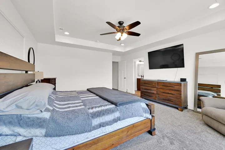 Spacious room featuring tray ceiling with recessed lighting and a ceiling fan