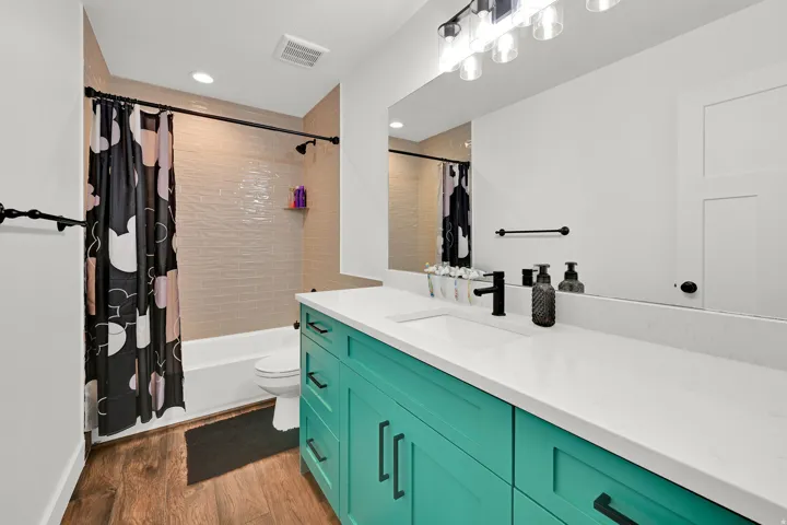 Modern bathroom featuring a teal vanity with a white countertop and integrated sink