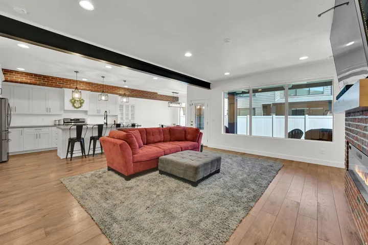 Open-concept living space featuring wood-finish flooring, recessed lighting, and a brick accent wall