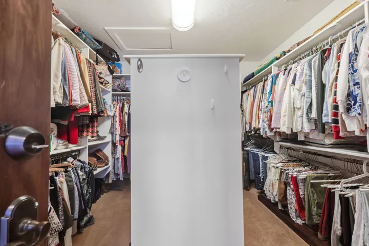 Walk-in closet featuring extensive built-in shelving, multiple hanging rods, and central storage island