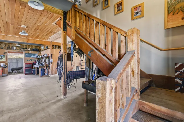 Robust wooden staircase with a substantial newel post and balusters, featuring a wood-finish handrail