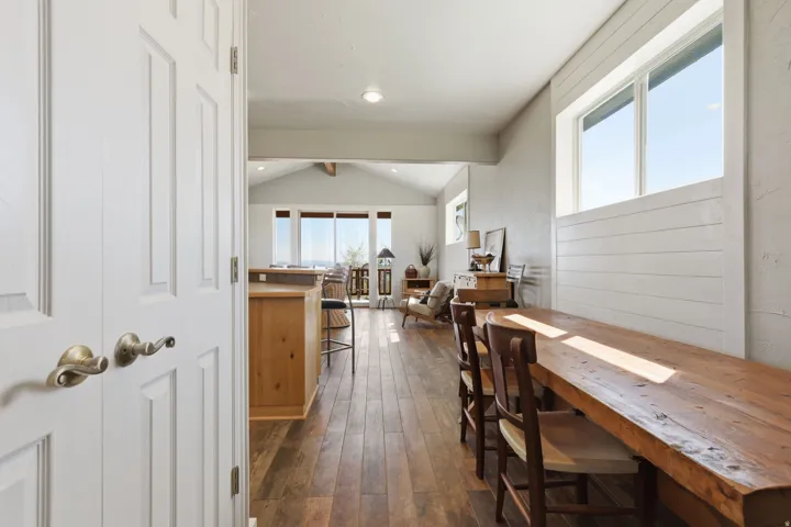 Open concept living area featuring wood-finish flooring, a vaulted ceiling, and ample natural light from multiple windows
