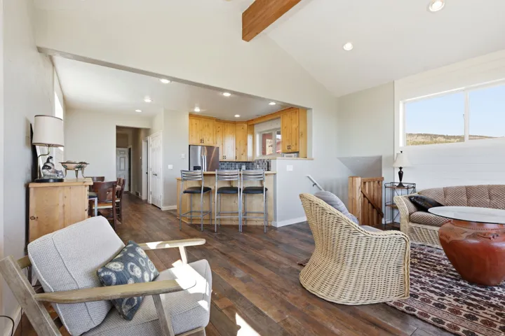 Open-concept living space featuring wood-finish flooring, recessed lighting, and a vaulted ceiling with exposed beam