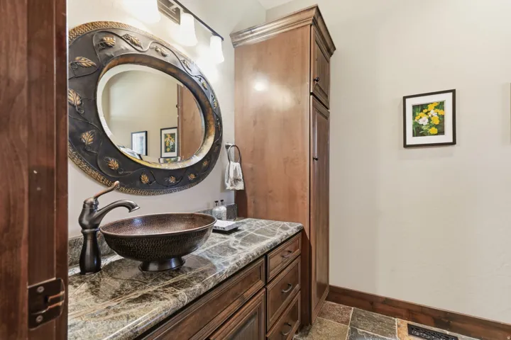 Custom vanity with a vessel sink, stone countertop, and bronze-finish hardware