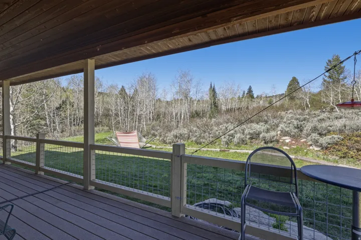 Covered outdoor deck featuring composite decking, wood posts, and wire mesh railings
