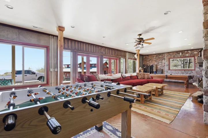 Spacious recreation room featuring exposed brick accents and wood-finish flooring