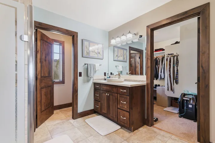 Bathroom vanity featuring a vessel sink, light countertop, and wood-finish cabinetry
