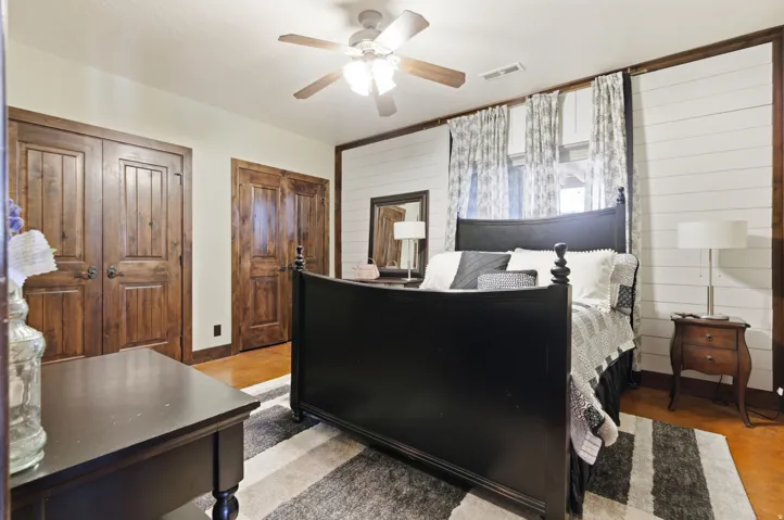 Room featuring rich wood-finish doors and trim, shiplap accent wall, ceiling fan with integrated lighting, and polished concrete flooring