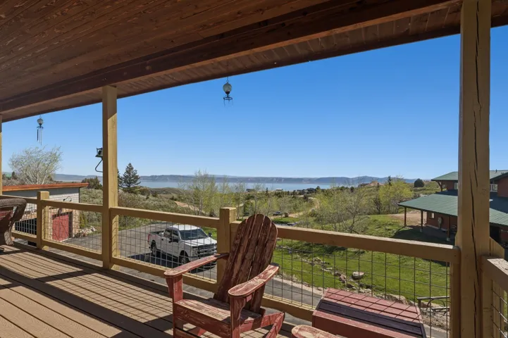Covered porch with exposed wood ceiling beams, wood-finish decking, and cable railing system