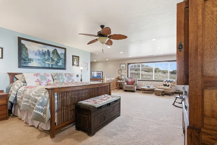Spacious room featuring broadloom carpet, a wide window with exterior landscape beyond, a ceiling fan, recessed lighting, and a light blue wall finish