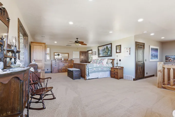 Expansive carpeted room featuring recessed lighting, a ceiling fan, and multiple wood-paneled doors