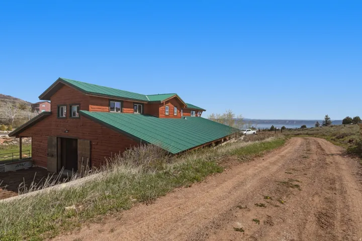 Rustic-style exterior featuring log siding, a green metal roof, and multiple windows
