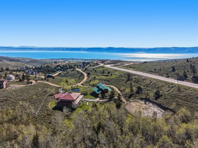 Expansive natural landscape featuring two distinct properties, a paved road, and a distant body of water
