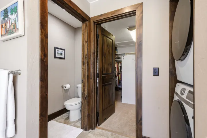 Powder room featuring a toilet, light-toned tile flooring, and wood-finish door frames