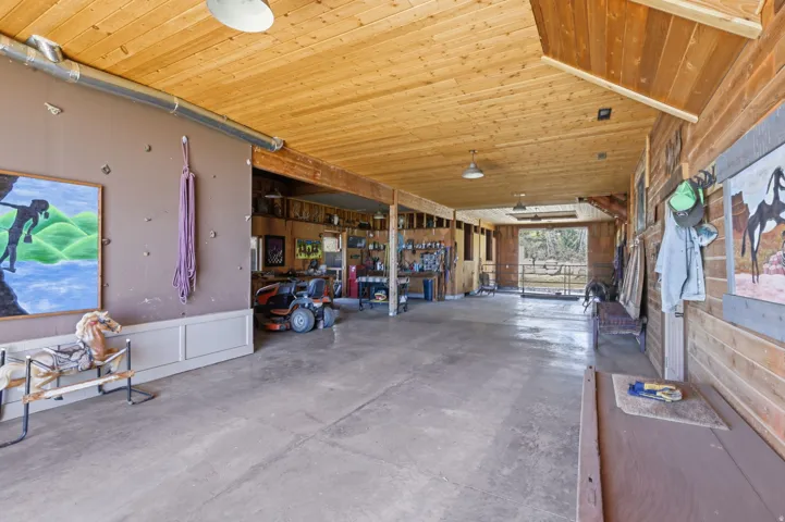 Spacious interior structure featuring exposed wood plank ceiling, concrete flooring, and extensive wood paneling