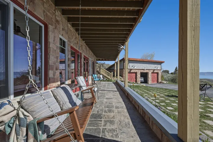 Expansive covered patio featuring stone-look flooring, a stone exterior, and multiple glass doors with red trim