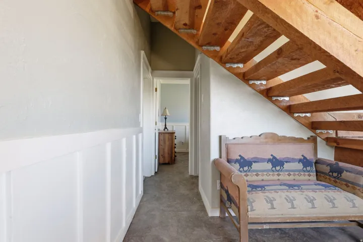 Open tread wood staircase with exposed stringers, complemented by board and batten wainscoting and a textured wall finish