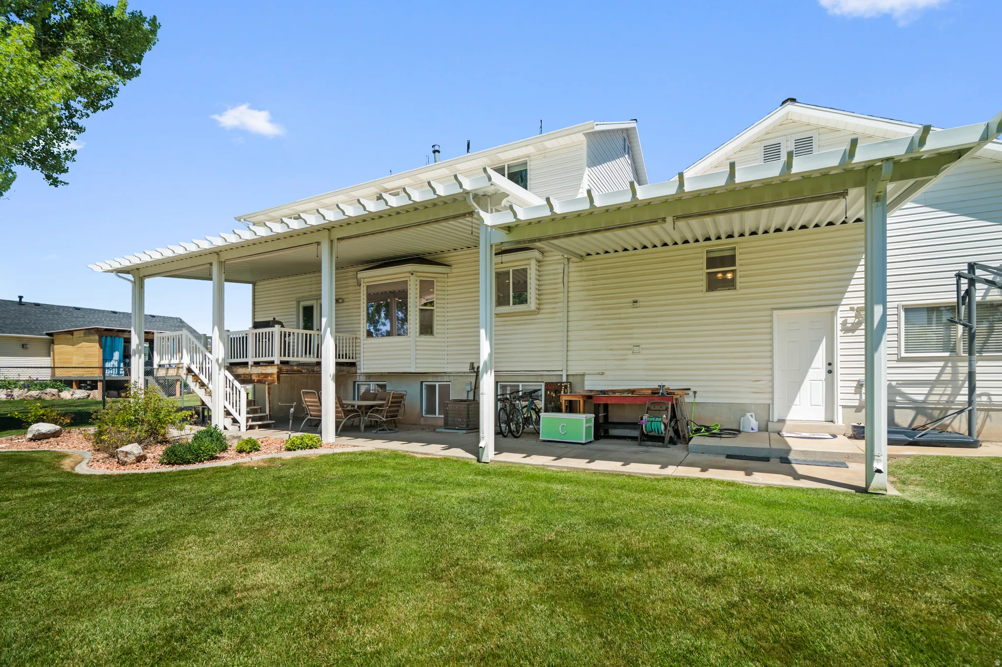 Expansive backyard featuring a manicured lawn, an extended patio with a pergola, and a multi-level deck with white railings