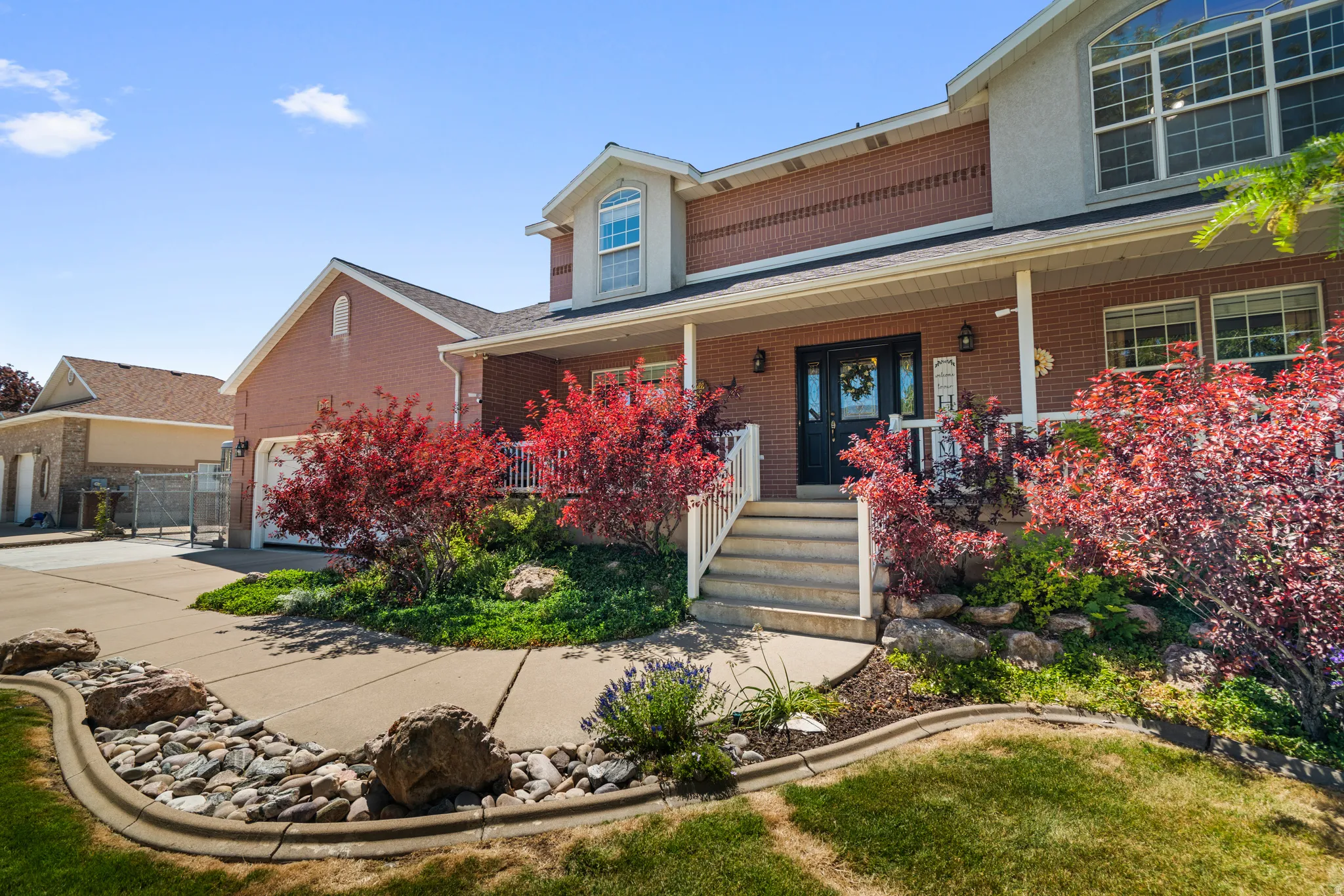 Brick exterior residence featuring a covered front porch with white railings, entry door, and multi-paned windows