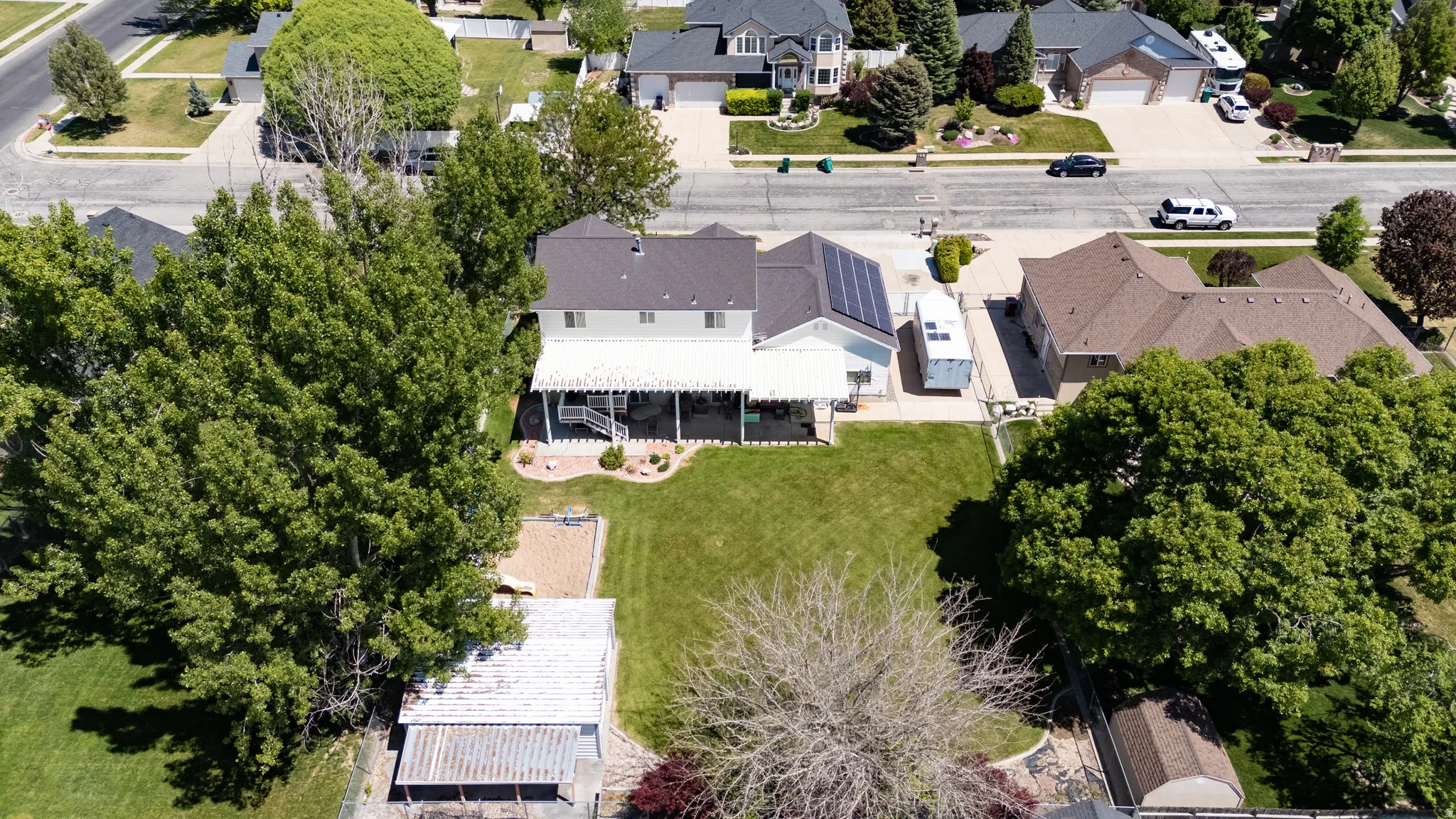 Expansive backyard featuring a manicured lawn, mature trees, and a detached outbuilding