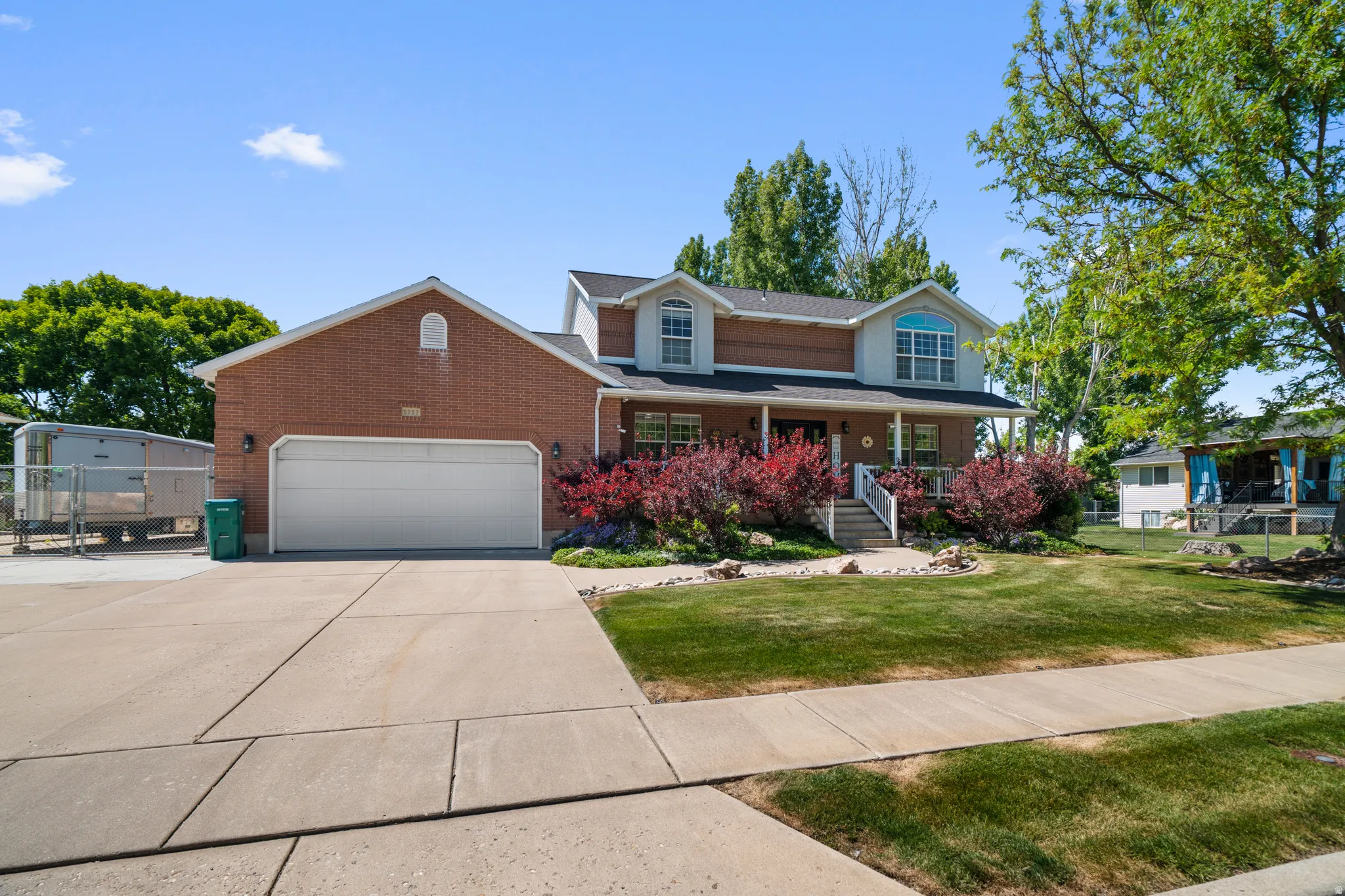 Two-story residence featuring a brick facade with a columned front porch and a two-car garage